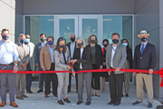 many people gathered outside the new building with ceremonial ribbon cutting