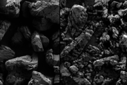 Real scanning electron microscope image of TATB powder, alongside a hypothetical scanning electron microscope image of TATB powder made to optimize its peak stress. The hypothetical image is made of smaller grains. 