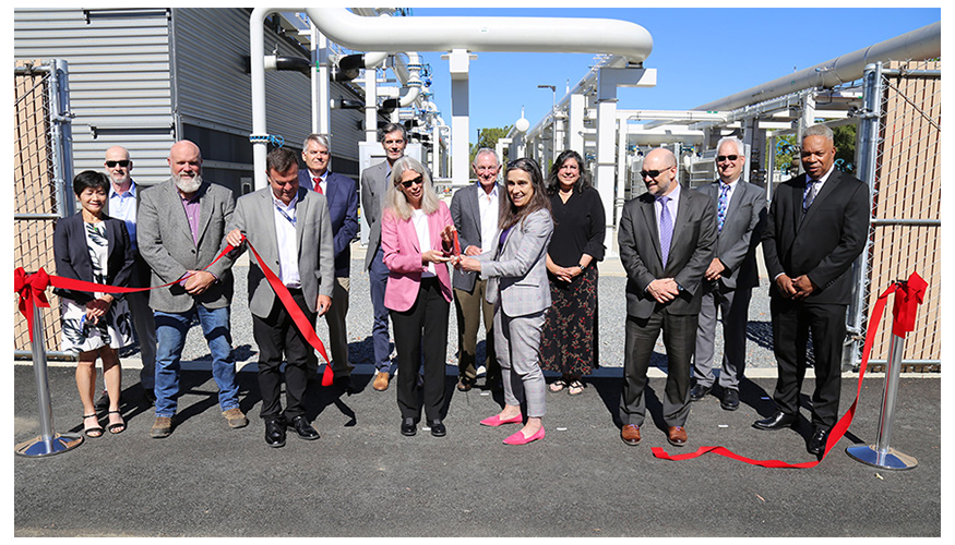 thirteen people assemble in front of the ECFM infrastructure to cut the ceremonial red ribbon