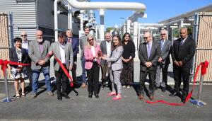 13 people cut a red ribbon in front of the new building
