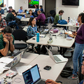 wide shot of hackathon attendees mingling and working on laptops