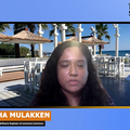 Screen shot of Nisha speaking to the camera with a virtual background behind her